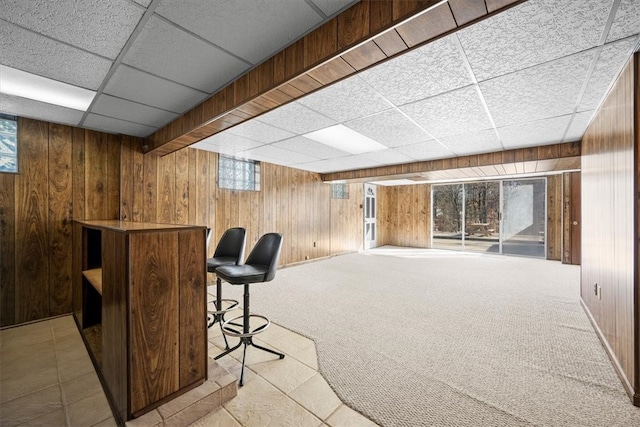 bar featuring wood walls, a paneled ceiling, and light carpet