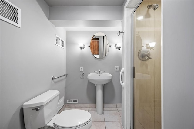 bathroom featuring a shower with door, tile patterned flooring, and toilet