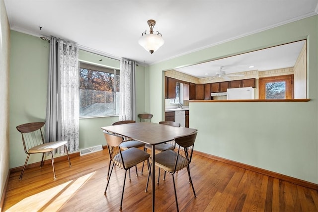 dining room with ceiling fan, crown molding, and light hardwood / wood-style flooring