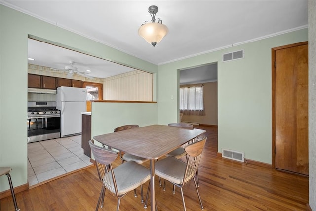 dining space featuring light wood-type flooring, ceiling fan, and crown molding