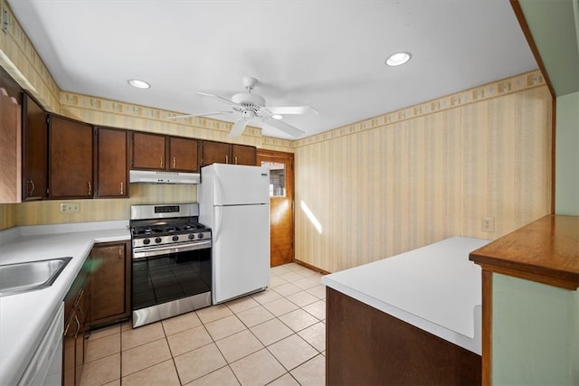 kitchen with dark brown cabinetry, sink, ceiling fan, light tile patterned floors, and white appliances