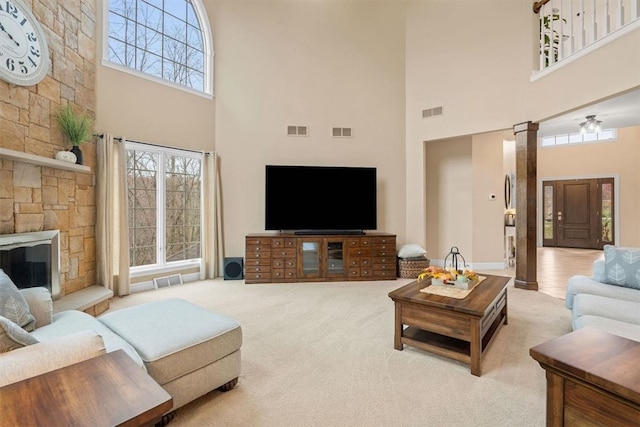 living room featuring a fireplace, a high ceiling, light carpet, and ornate columns