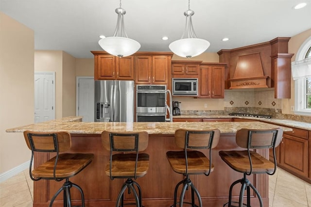 kitchen featuring a kitchen bar, stainless steel appliances, a center island, custom range hood, and decorative light fixtures