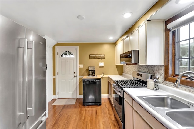 kitchen with backsplash, sink, stainless steel appliances, and light hardwood / wood-style floors