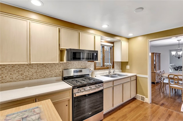 kitchen featuring appliances with stainless steel finishes, tasteful backsplash, sink, a chandelier, and light hardwood / wood-style floors