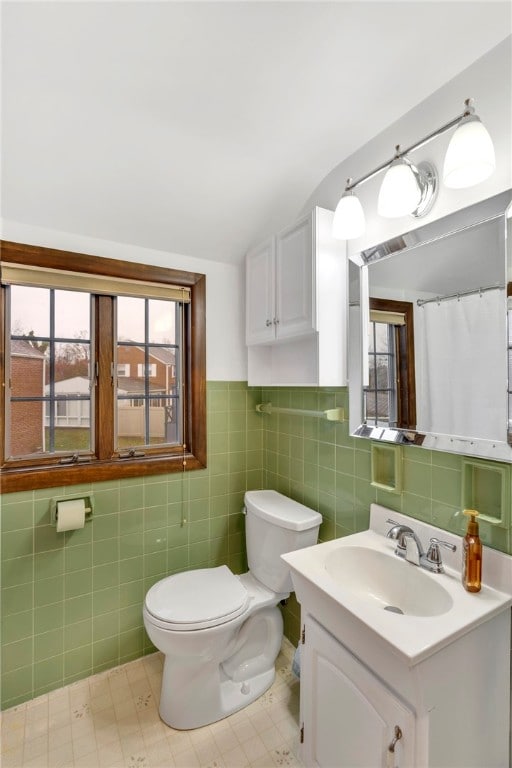 bathroom with vanity, tile walls, and toilet