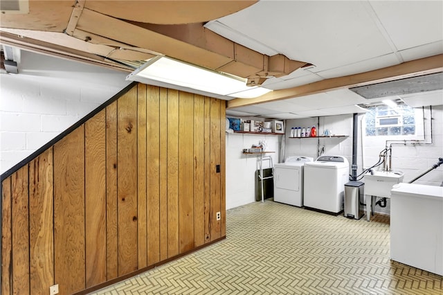 laundry room with wooden walls, washer and clothes dryer, and sink