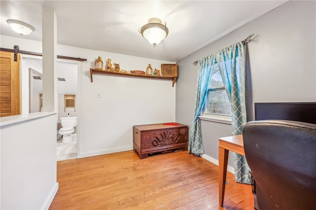 office space with a barn door and light wood-type flooring