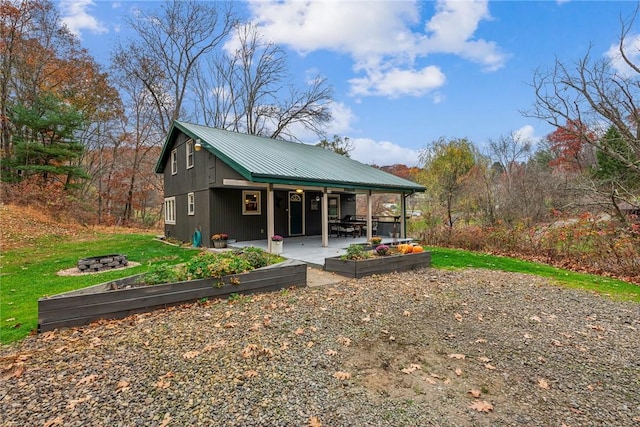 139 Willow Rd, Washington Twp Wml, PA 15613 - rear view of property with metal roof, a fire pit, a patio, and a yard