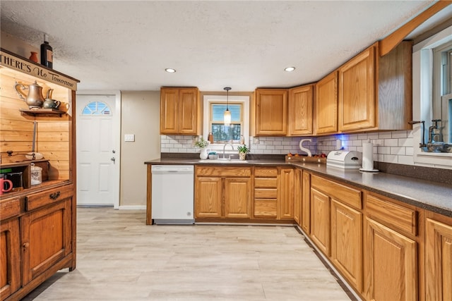 kitchen featuring sink, hanging light fixtures, white dishwasher, a textured ceiling, and decorative backsplash