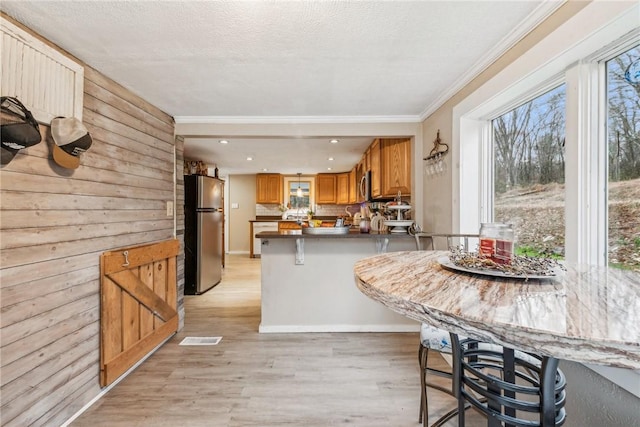 139 Willow Rd, Washington Twp Wml, PA 15613 - kitchen featuring appliances with stainless steel finishes, crown molding, a peninsula, light wood finished floors, and a breakfast bar area
