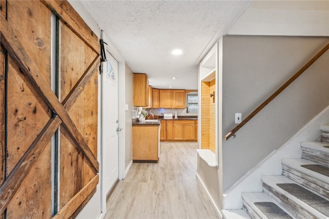 kitchen with a barn door, tasteful backsplash, and light hardwood / wood-style flooring