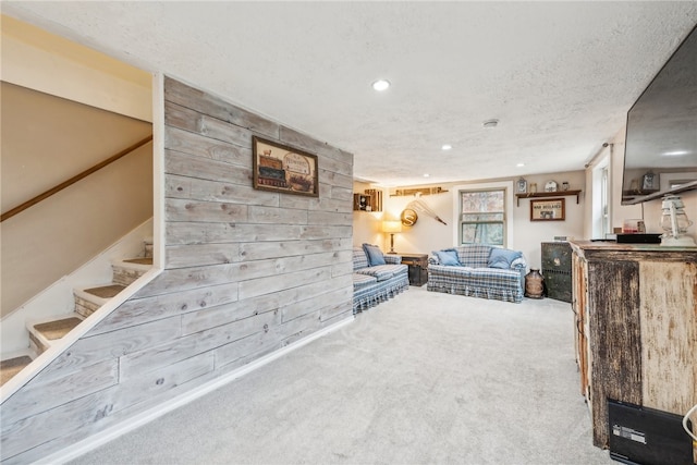 living room with carpet flooring, a textured ceiling, and wooden walls