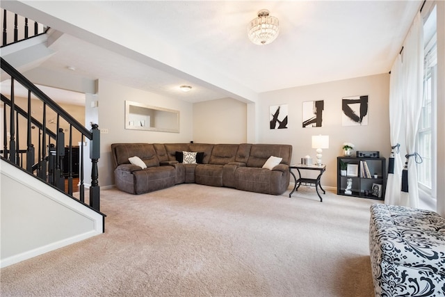 carpeted living room with a chandelier