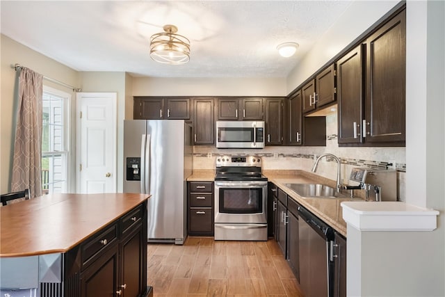 kitchen with a textured ceiling, appliances with stainless steel finishes, sink, and backsplash