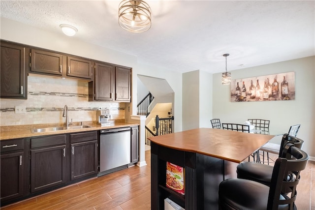 kitchen featuring backsplash, light wood-type flooring, pendant lighting, sink, and stainless steel dishwasher