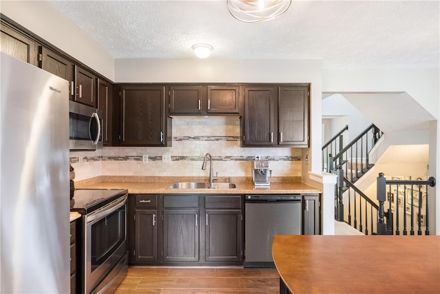 kitchen featuring sink, appliances with stainless steel finishes, tasteful backsplash, dark brown cabinets, and light hardwood / wood-style flooring