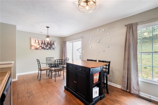 dining space with plenty of natural light, wood-type flooring, and a textured ceiling