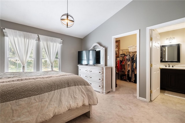 carpeted bedroom featuring ensuite bathroom, a spacious closet, vaulted ceiling, and a closet