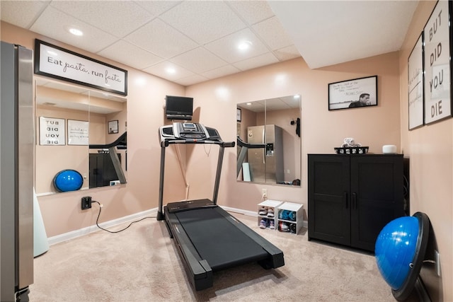 workout room with a paneled ceiling and light carpet