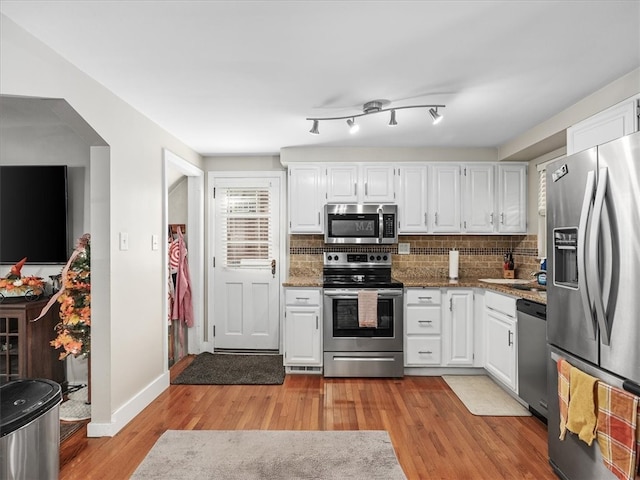 kitchen with stainless steel appliances, white cabinetry, and light wood-type flooring