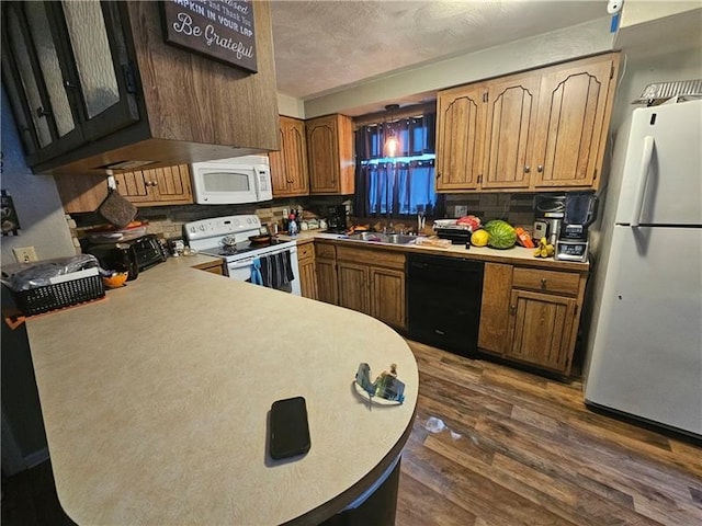 kitchen featuring backsplash, white appliances, dark hardwood / wood-style floors, sink, and kitchen peninsula