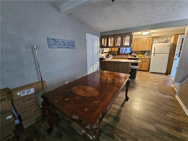 dining space with lofted ceiling with beams, light hardwood / wood-style flooring, and a textured ceiling