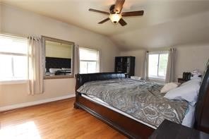 bedroom featuring light hardwood / wood-style floors, multiple windows, lofted ceiling, and ceiling fan