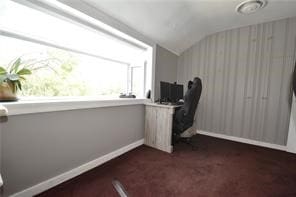 home office with lofted ceiling and dark carpet