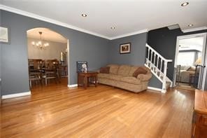 living room with a chandelier, wood-type flooring, and ornamental molding