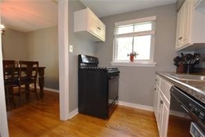 kitchen with white cabinets, light hardwood / wood-style floors, sink, and black appliances