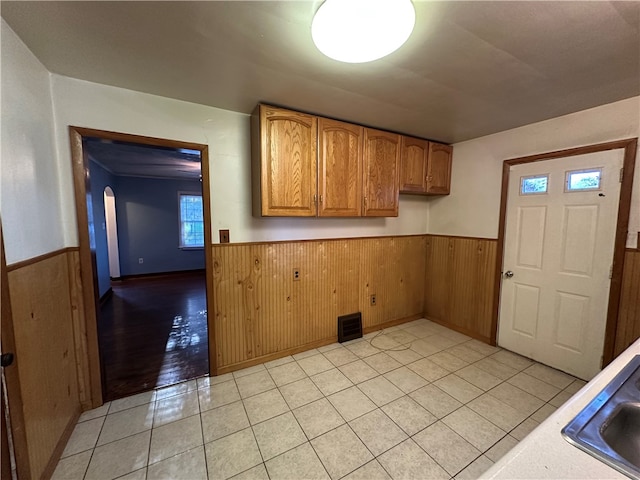 kitchen featuring wooden walls and light tile patterned flooring