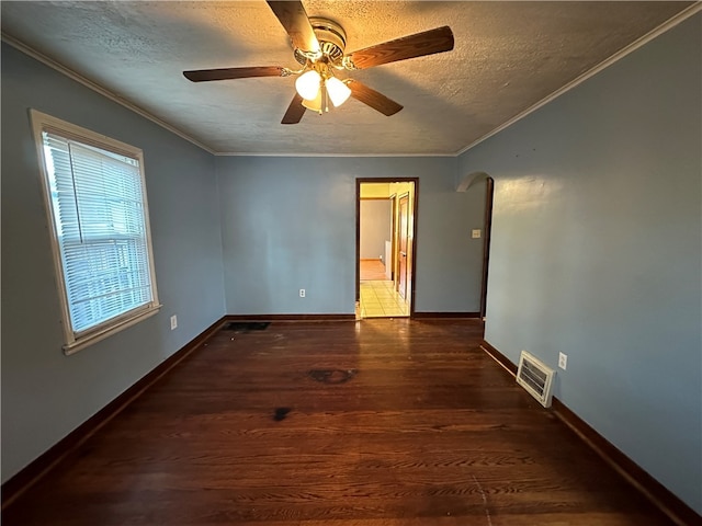 empty room with a textured ceiling, dark hardwood / wood-style flooring, ceiling fan, and crown molding