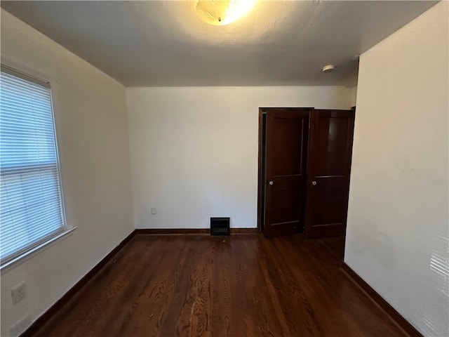 empty room featuring a healthy amount of sunlight and dark hardwood / wood-style flooring