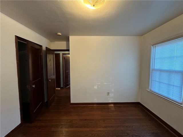 spare room featuring a healthy amount of sunlight and dark wood-type flooring