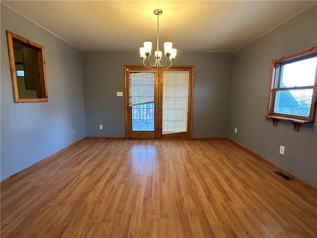 spare room featuring hardwood / wood-style flooring and an inviting chandelier