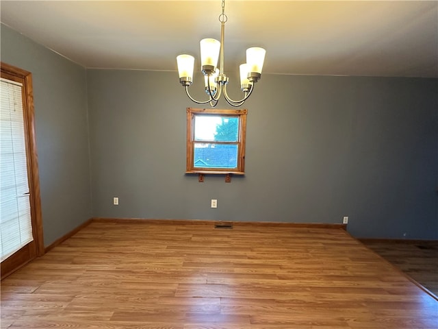 spare room with wood-type flooring and a notable chandelier