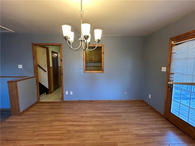 unfurnished dining area with a chandelier, light hardwood / wood-style flooring, and a healthy amount of sunlight