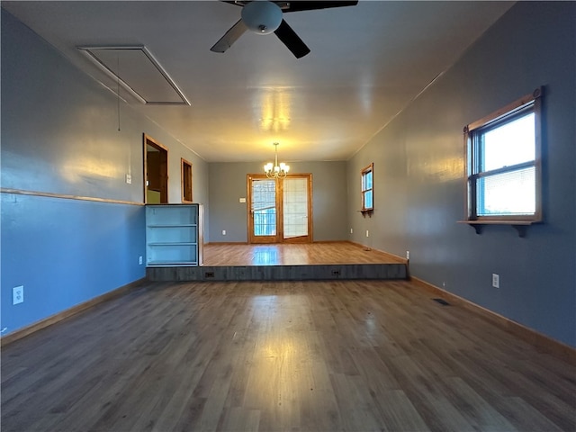 unfurnished living room featuring hardwood / wood-style floors and ceiling fan with notable chandelier