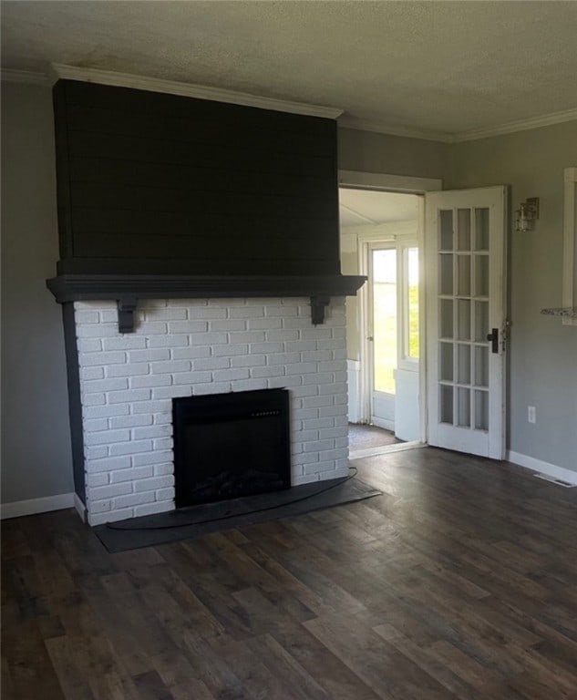 unfurnished living room featuring a brick fireplace, a textured ceiling, dark hardwood / wood-style floors, and crown molding