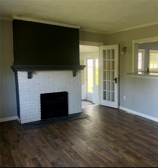 unfurnished living room with a brick fireplace, dark hardwood / wood-style floors, a textured ceiling, and crown molding