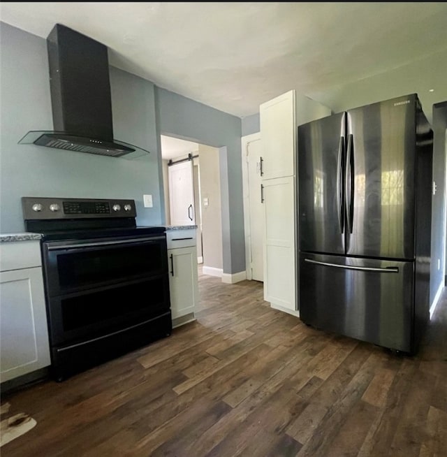 kitchen featuring white cabinetry, wall chimney exhaust hood, a barn door, stainless steel fridge, and electric range