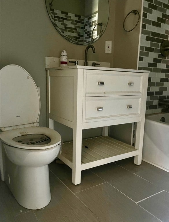 bathroom with toilet, vanity, a tub, and tile walls