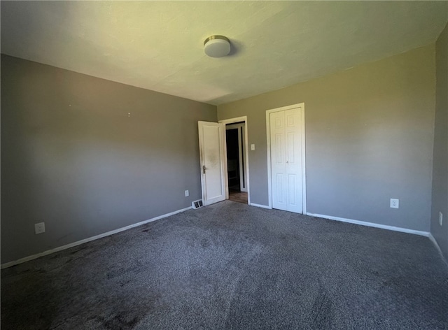 unfurnished bedroom with a closet and dark carpet