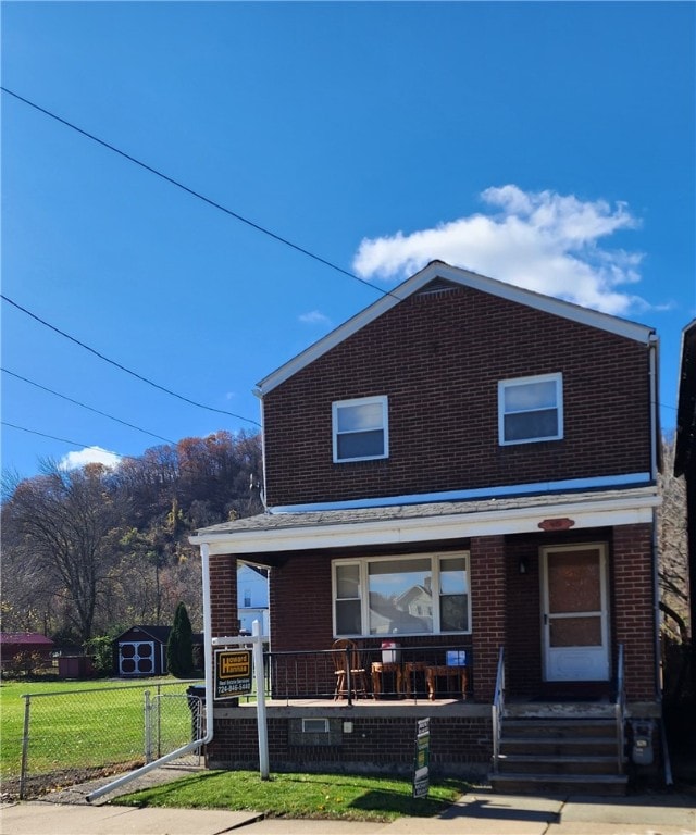 view of front facade featuring a front lawn, a storage shed, and a porch