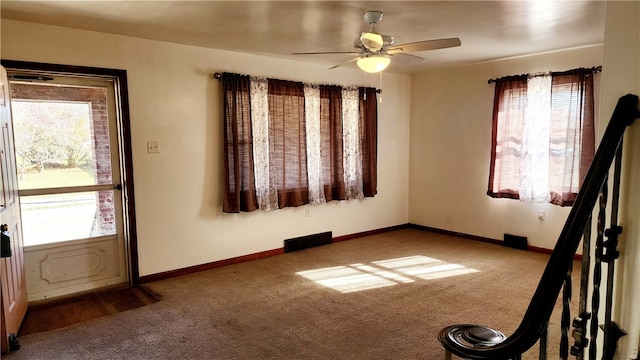 carpeted spare room featuring ceiling fan and plenty of natural light