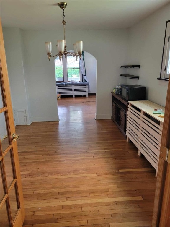 interior space with pendant lighting, hardwood / wood-style flooring, and a notable chandelier