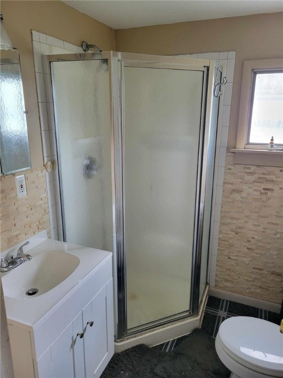 bathroom featuring toilet, an enclosed shower, vanity, and tile walls