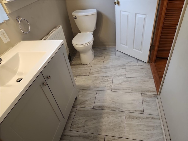 bathroom with toilet, radiator, and vanity