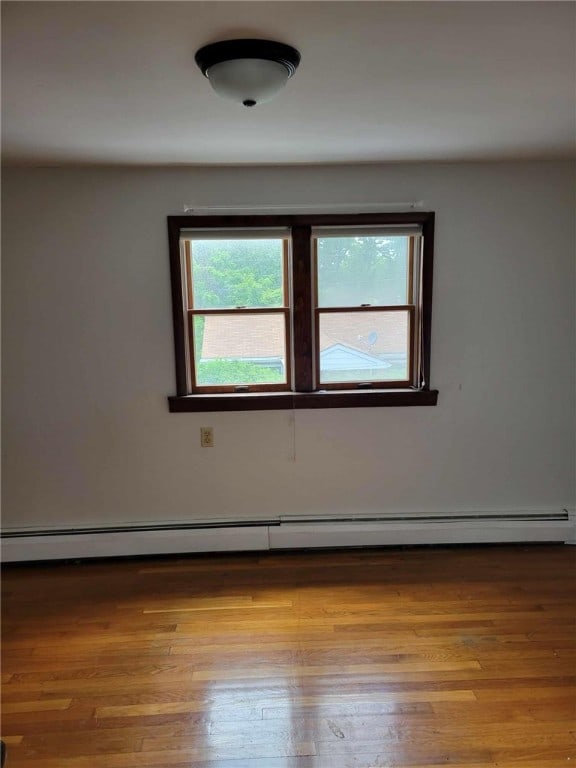 empty room with light hardwood / wood-style floors and a baseboard heating unit